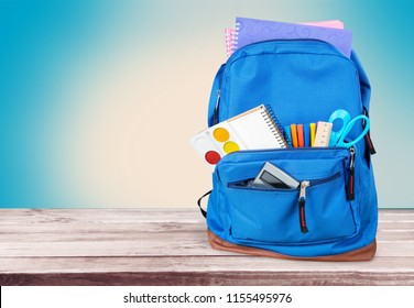 School Backpack with supplies on wooden background - Shutterstock ID 1155495976