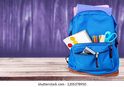 School Backpack with supplies on wooden background - Shutterstock ID 1205378950