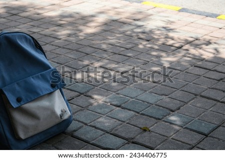 school Bag White and blue color, Tree shadow backdrop on the footpath, floor, bricks pattern