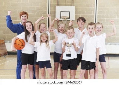 School Basketball Team And Coach Celebrating Victory With Trophy