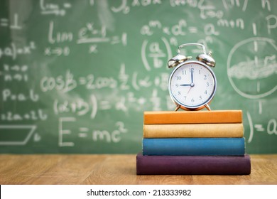 school books with alarm clock on green school board background  - Powered by Shutterstock