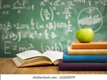 School books with apple on desk over green  school board background - Shutterstock ID 213333979