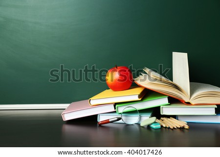 School books on desk near chalkboard