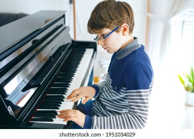 School Boy With Glasses Playing Piano In Living Room. Child Having Fun With Learning To Play Music Instrument. Talented Kid During Homeschooling Corona Virus Lockdown.