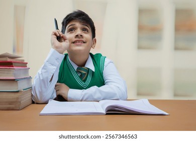 School boy is looking up while studying at class