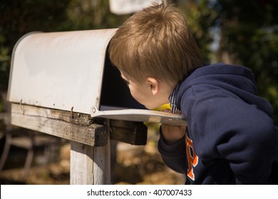 School Boy Opening A Post Box And Checking Mail. Kid Waiting For A Letter, Checking Correspondence And Looking Into The In The Metal Mailbox.