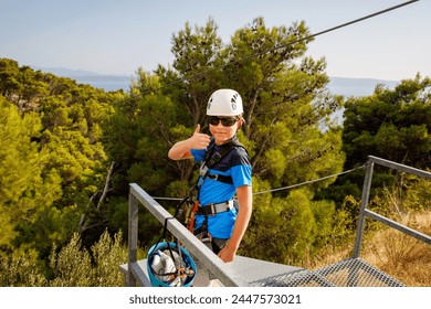 School boy preparing for zipline adventure. Happy active child put safety helmet on head. Summer fun with climbing in mountains. - Powered by Shutterstock