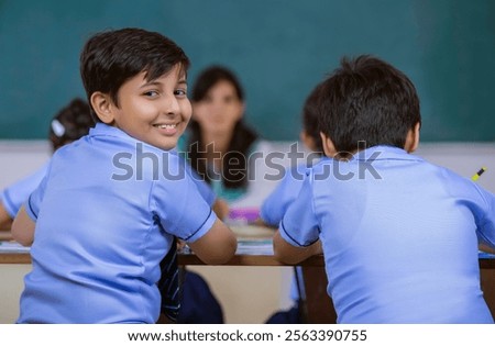 school boy smiling while teacher is sitting in class