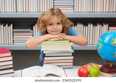 School boy with stack of books in library. School child. Kid boy from elementary school. Pupil go study. Clever schoolboy learning. Kids study, knowledge and education.