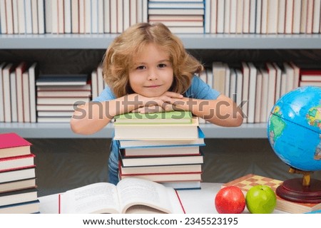 School boy with stack of books in library. School child. Kid boy from elementary school. Pupil go study. Clever schoolboy learning. Kids study, knowledge and education.