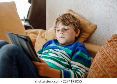 School boy with tablet computer. Schoolchild study online. Electronic device for learning, studying and playing at home. Little boy with laptop pc. Gadget and screen time for children. Kid at home. - Powered by Shutterstock