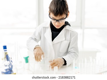 School Boy Wearing Protection Glasses Doing Chemistry Experiment In Elementary Science Class. Pupil With Equipment Tubes In Lab