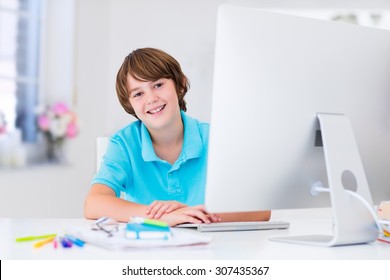 School Boy Working On Personal Computer At Home. Student Doing Homework Using Modern Pc In Classroom. Kids Studying With Digital Devices. Children Study In White Class Room. Child Learning.