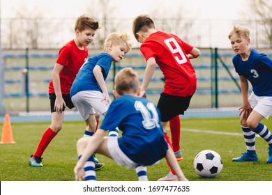 School Boys Playing Football Game. Young Players Kicking Soccer Ball On Sports Grass Pitch. Happy Children Compete On A Field