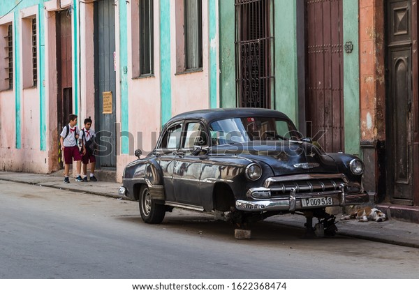 School boys walk passed a sleeping dog & an\
old timer on bricks on their way home in Centro Havana, Cuba in\
November 2015.