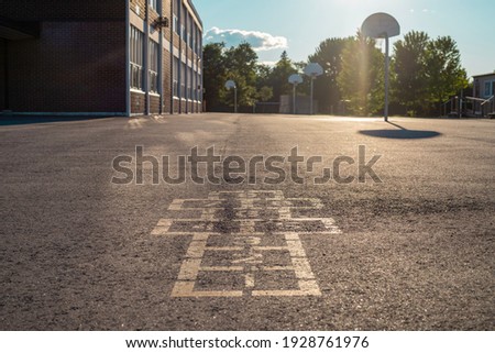 School building and schoolyard in the evening. Hopscotch game on asphalt at the school yard playground.