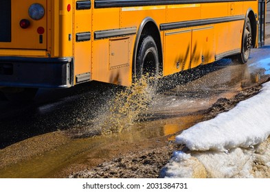 School Bus Driving Through Pothole Splashing Muddy Water On City Street.