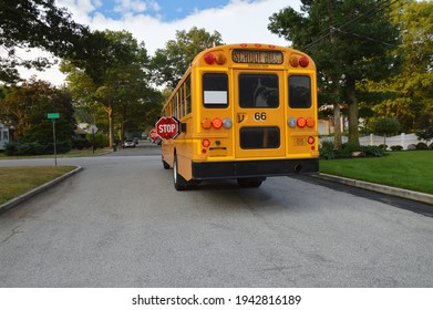 School Bus With Flashing Red Lights And Stop Signs Extended On Suburban Neighborhood Street