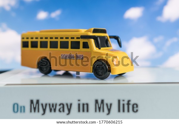 School bus for Student transport for children\
transports service on stack books with word on myway in my life on\
blue sky background. Transport service regularly to transfer\
students to school