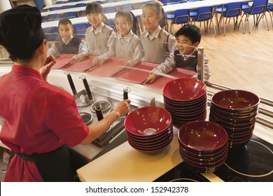 School Cafeteria Worker Serves Noodles To Students