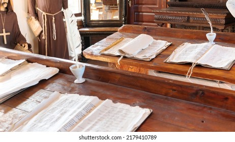 School In A Catholic Jesuit Monastery. Education In The Middle Ages. Ancient Manuscripts And Parchment With A Quill Pen Lie On Aged Wooden Desks. Class In A Medieval University With Monks As Teachers.