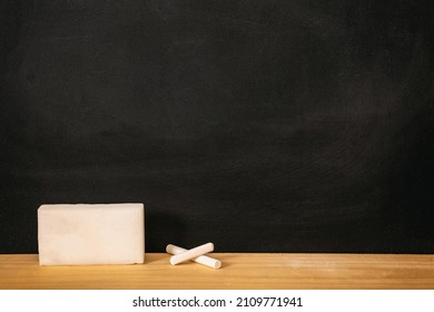 School chalkboard, blank empty black board, white chalk piece and sponge on wooden frame sill, copy space