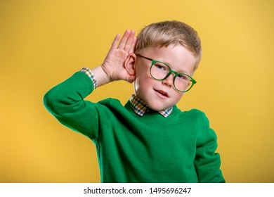 School Child Boy Holds Hand Near Ear. Funny Boy In Green Glasses And Sweater  Listens Carefully. Family Communication With Kid. Hear Parent. Interesting Education News