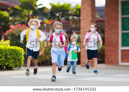 School child wearing face mask during corona virus and flu outbreak. Boy and girl going back to school after covid-19 quarantine and lockdown. Group of kids in masks for coronavirus prevention. 