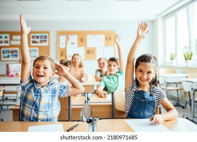 School children in classroom at lesson. Little children raising hands up and having fun in class. - Shutterstock ID 2180971685