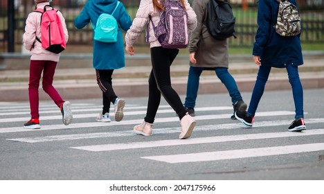 School children cross the road in medical masks. Children go to school - Shutterstock ID 2047175966