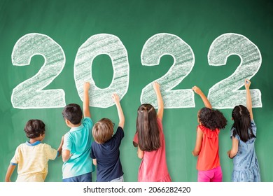 School children drawing 2022 new year on the chalkboard.