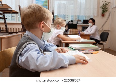 School Children In Medical Face Mask Are Learning In The Half Empty Classroom During Epidemic Of Flu.