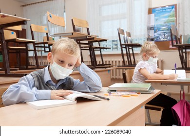 School Children In Medical Face Mask Are Learning In The Half Empty Classroom During Epidemic Of Flu.