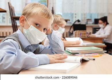 School Children In Medical Face Mask Are Learning In The Half Empty Classroom During Epidemic Of Flu.