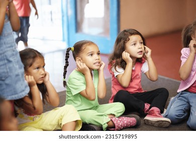 School children on floor listening to teacher for anatomy education, hearing exercise and learning in classroom. Class, group and kids on ground with attention, discipline and kindergarten or creche - Shutterstock ID 2315719895