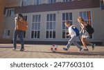 school children play football. sport people education and family concept. a group of school children with backpacks having fun playing football in the schoolyard lifestyle