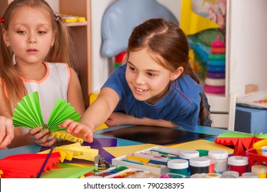 School children with scissors in kids hands cutting paper with teacher in class room. Development and social lerning. Children's project in kindergarten. Newcomer in a children's team.
