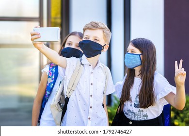 School Children Wearing Protective Face Masks Taking Selfie At School Reopening – New Normal Concept With Happy Kids Having Fun After Classes Were Open And Corona Virus Lockdown And Quarantine Ended