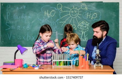 School Club Education. Discover And Explore Properties Of Substances Together. Interests And Topic Club. Teacher And Pupils Test Tubes In Classroom. Older Kids Help Younger. Chemistry Themed Club.