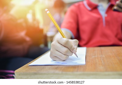 School Concept: Taking Test In College Or University Campus In America. Selective Focused Picture Of Student In The Classroom Of High School Final Exam On Essay Writing. Girl's Hand Holding Pencil