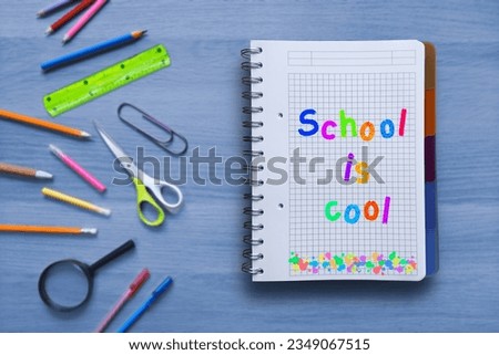 School is cool. Bright inscription in a notebook. Multicolored neon letters. Notepad with slogan on table with school supplies. The pleasure and joy of learning. Happy childhood without bullying.