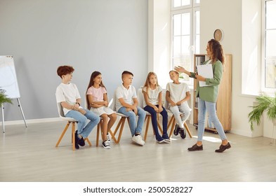 School counselor working with students. Children's psychologist meeting with group of kids. Boys and girls together with woman teacher preparing for school event and rehearsing role play skit - Powered by Shutterstock