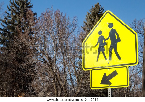 School crossing sign against\
trees 