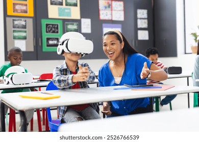 In school, diverse group of students and their teacher exploring virtual reality. The biracial teacher wearing blue shirt guiding student with VR headset, learning, education, unaltered - Powered by Shutterstock