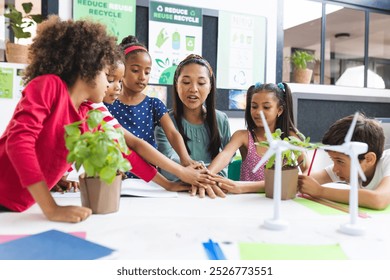 In school, diverse group of students and their teacher are engaging with plants in the classroom. They are wearing casual clothes and focusing on a green project, unaltered. - Powered by Shutterstock