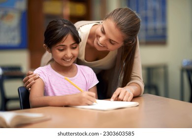 School, education or study with a student and teacher in a classroom together for writing or child development. Learning, scholarship and teaching with a woman educator helping a girl child in class - Powered by Shutterstock