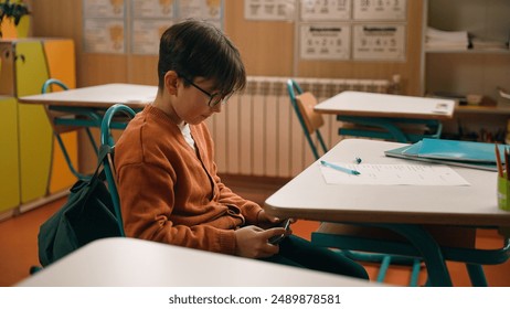 School education studying Caucasian boy little son schoolboy kid child pupil student schoolboy at class lesson gadget addict mobile phone addiction playing online video game hide smartphone under desk - Powered by Shutterstock