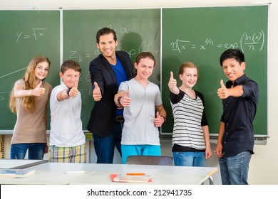 School And Education - Teacher And Students Stand In Front Of A Blackboard With Math Work In A Classroom Or Class 