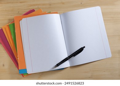 School exercise books and pen on a wooden background. View from above - Powered by Shutterstock