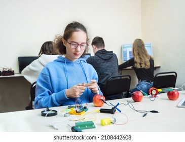 School Experiment With Apples. School Students Extract Electricity From Apples, Use Of The Energy Of A Chemical Reaction. Learning At Table STEM And STEAM Engineering Science Education Class.